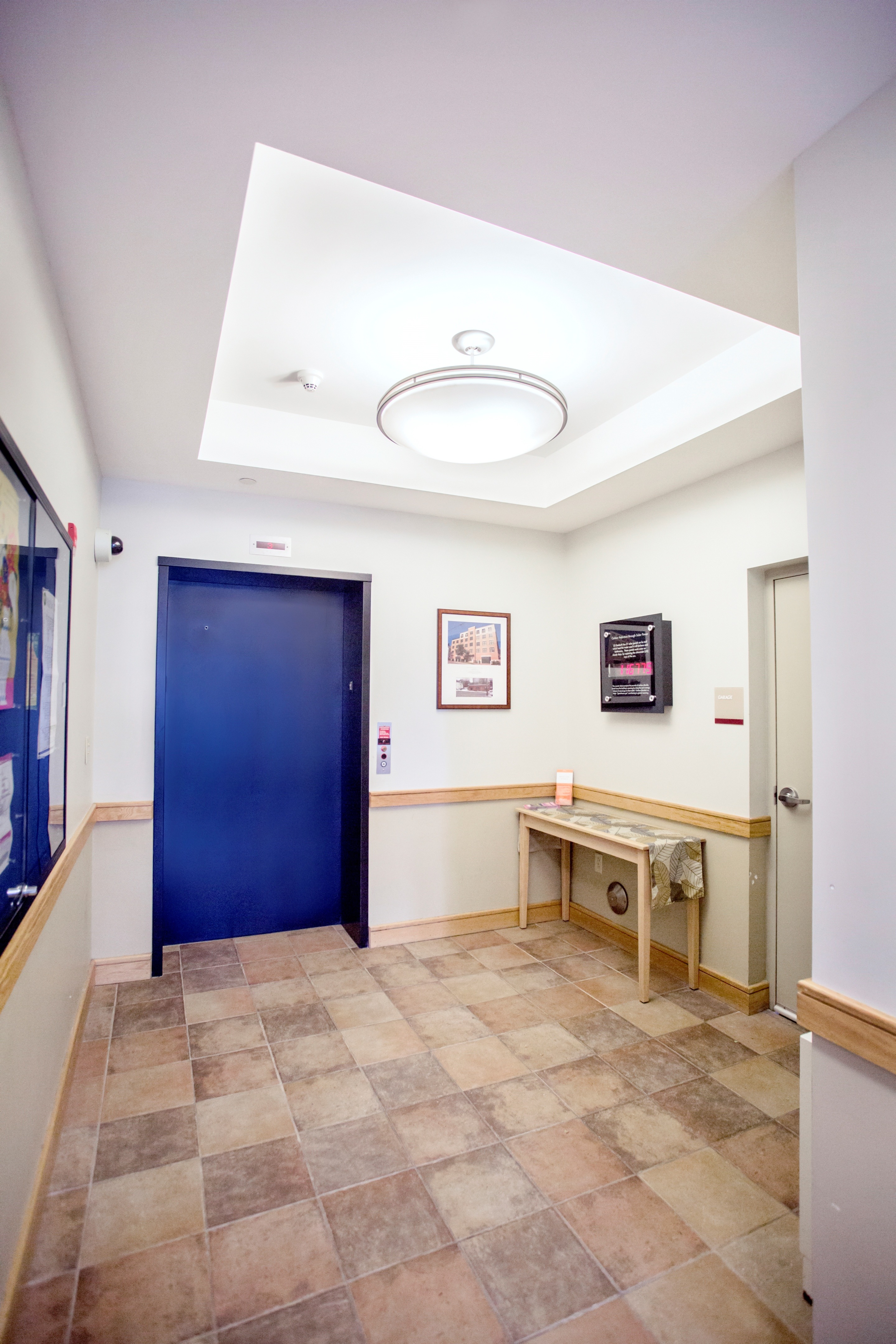 A hallway with a blue door and a bench.